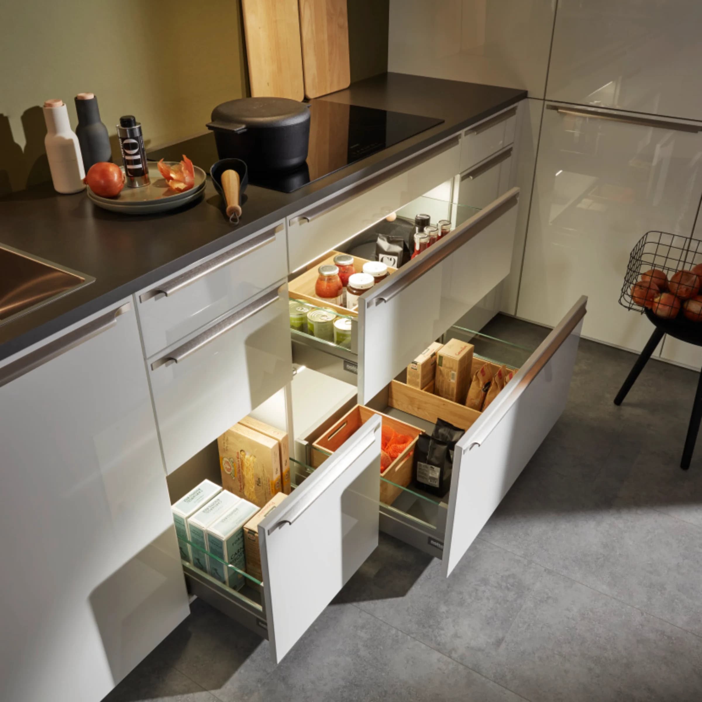 A modern kitchen with open drawers and cooking utensils on the countertop by Nolte Kitchen.