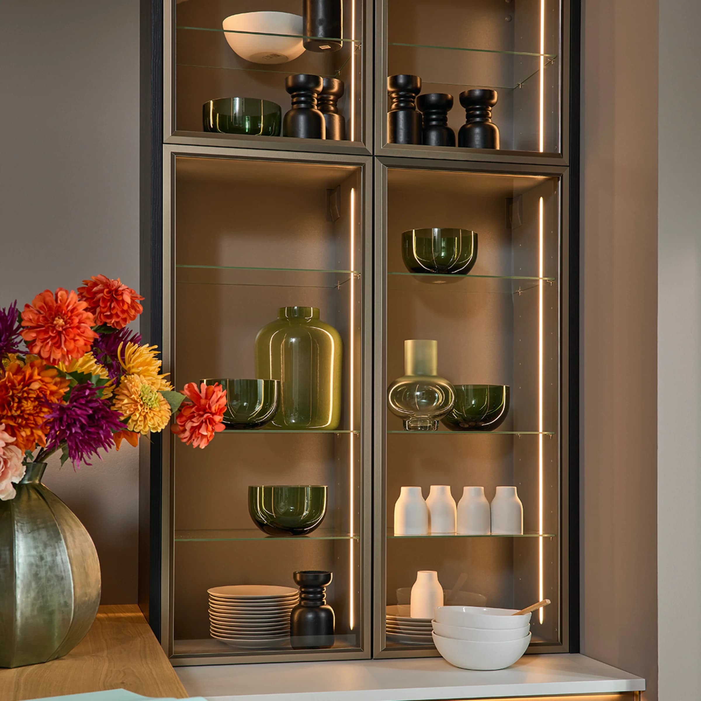An elegant living room shelf with glass vases and dishes, matching Nolte Living.